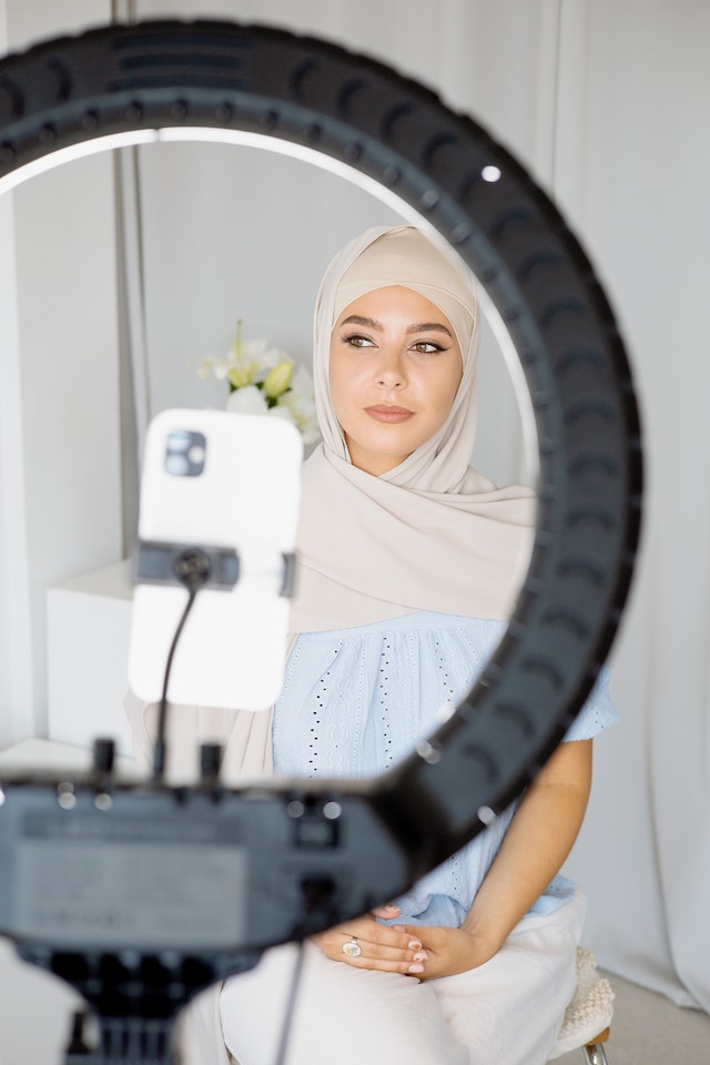 A woman sitting and recording a TikTok.