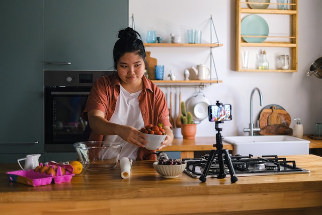 Una chica grabando un vídeo en TikTok mientras cocina. 