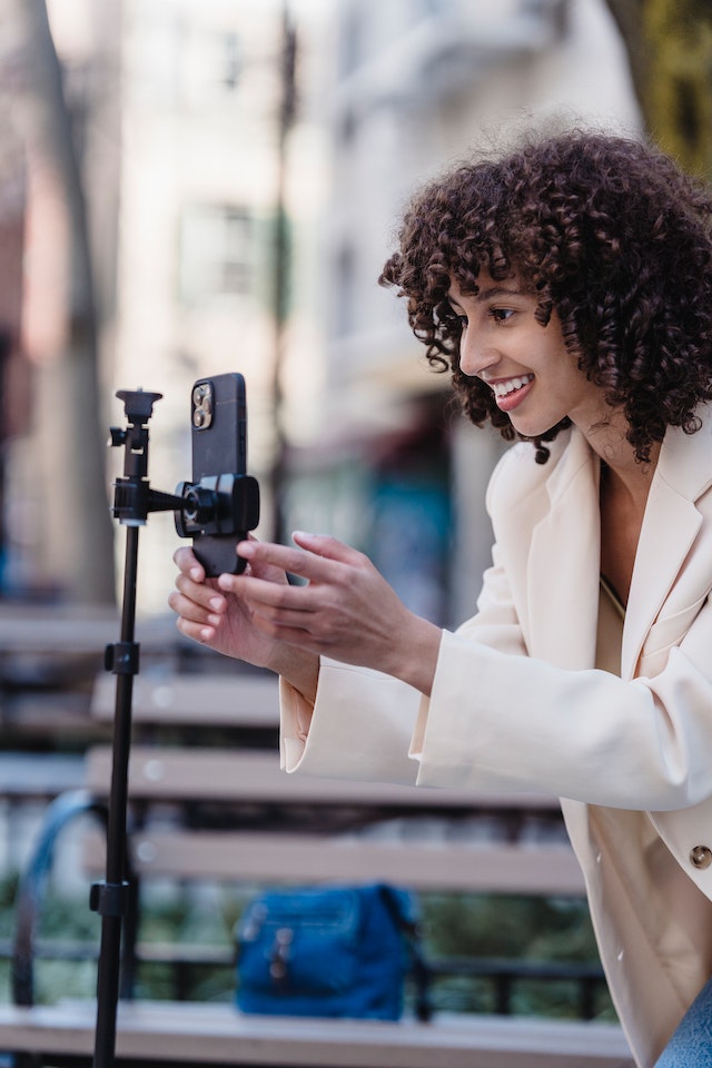 A woman recording a video for TikTok outside.