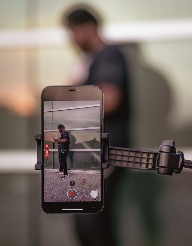 Um homem de pé e usando seu smartphone enquanto grava um vídeo para o TikTok.