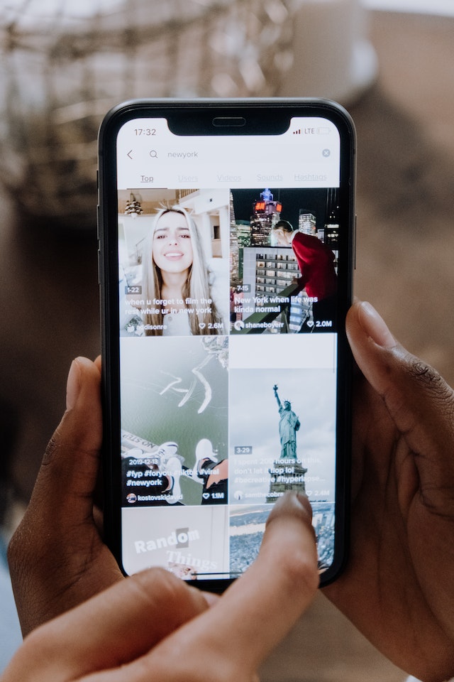 Jemand hält sein Telefon in der Hand und schaut sich TikTok-Videos an. 