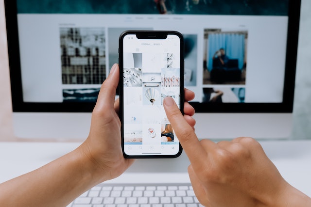 A person using his smartphone in front of his PC.