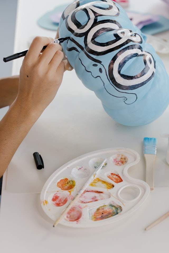 A person decorating a blue pumpkin for Halloween. 