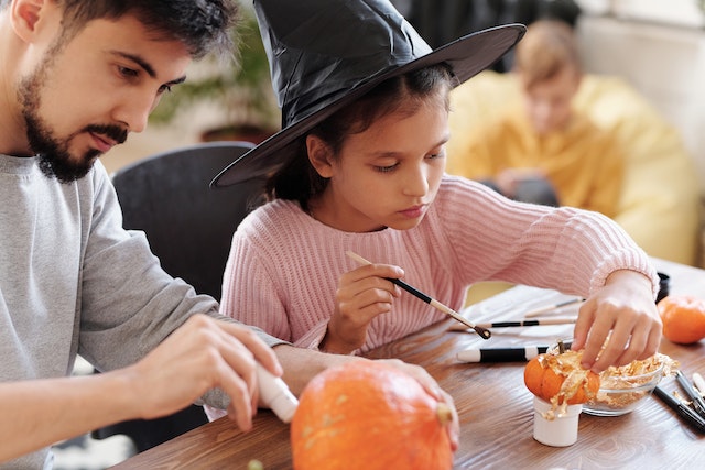 Un padre y su hija decorando calabazas para Halloween.