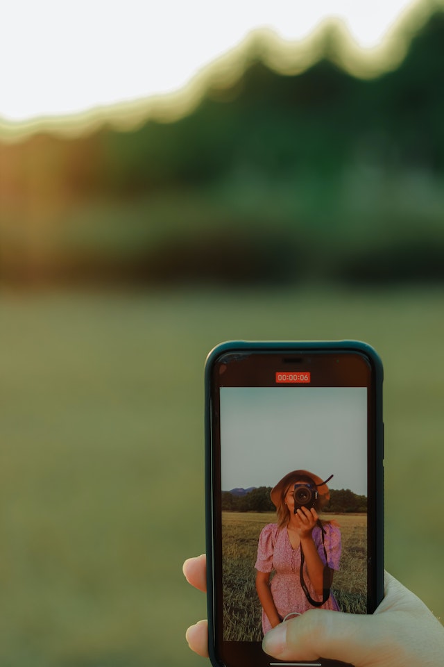 Uma garota gravando a si mesma com a câmera do telefone para o TikTok. 