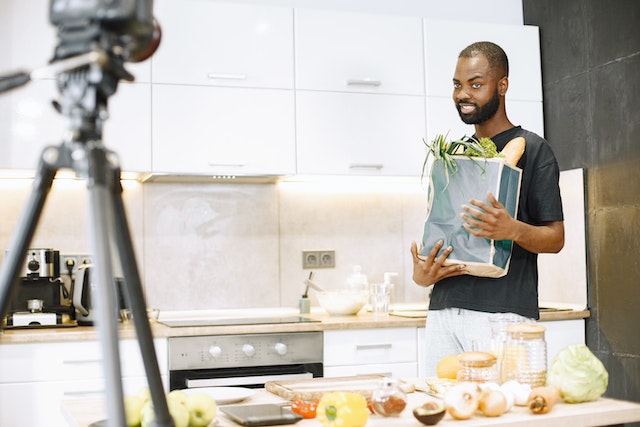 A man recording a TikTok while cooking.