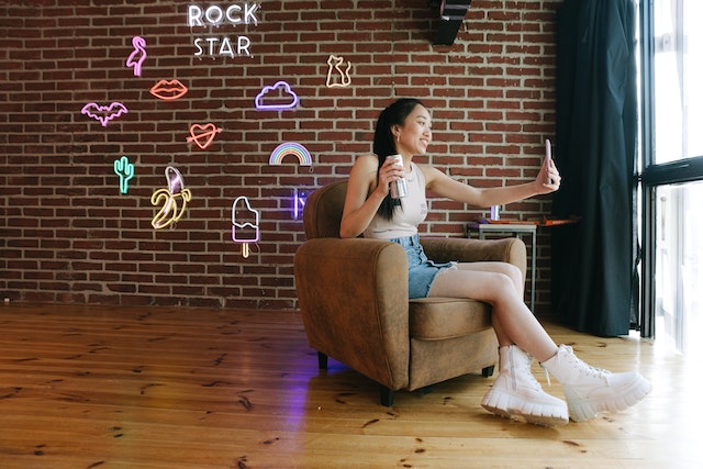 A girl sitting and holding her smartphone to record a TikTok. 