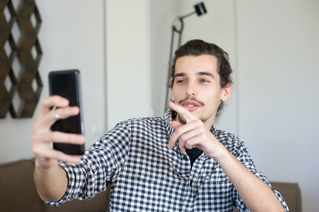 Um homem com uma camisa xadrez transmitindo ao vivo com seus fãs.