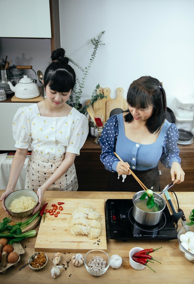 Zwei Mädchen kochen eine Schüssel Ramen nach einem trendigen Rezept. 