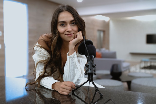 Uma garota posando com um microfone e gravando um vídeo.