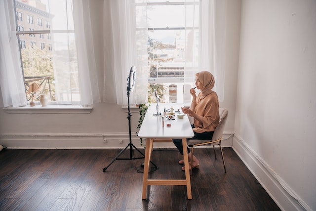 A girl doing her makeup and recording a video for TikTok.