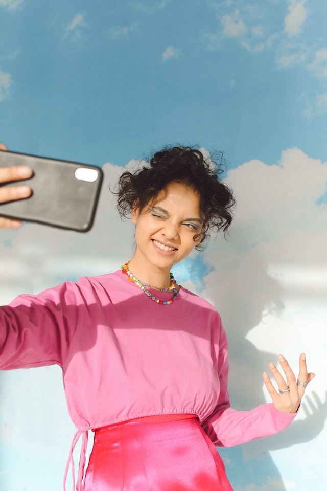 A girl in a pink sweater posing for a TikTok video.