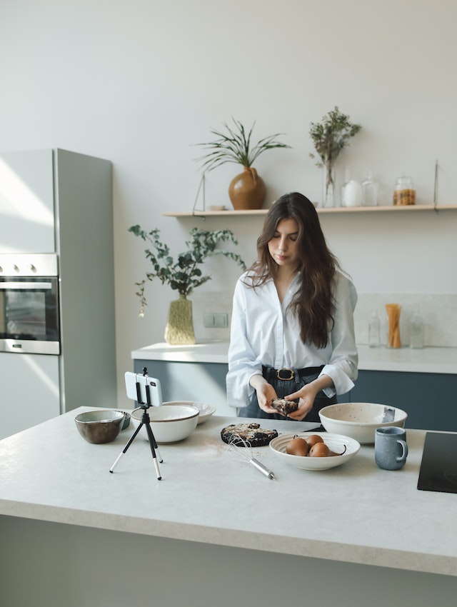 Una mujer grabando un vídeo TikTok de sí misma cocinando. 