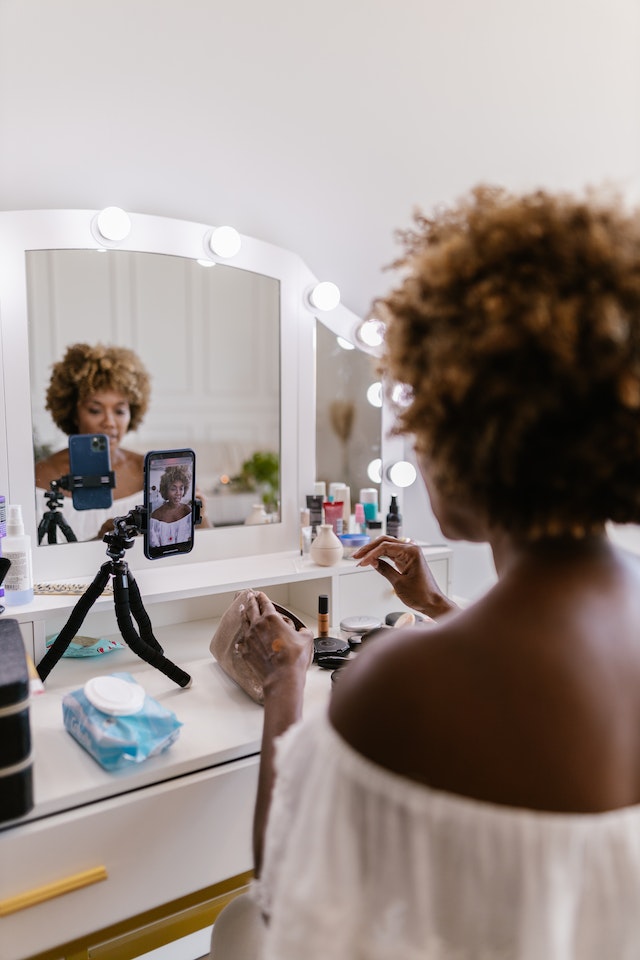 Een vrouw die zichzelf opneemt terwijl ze make-up doet voor een TikTok-video. 