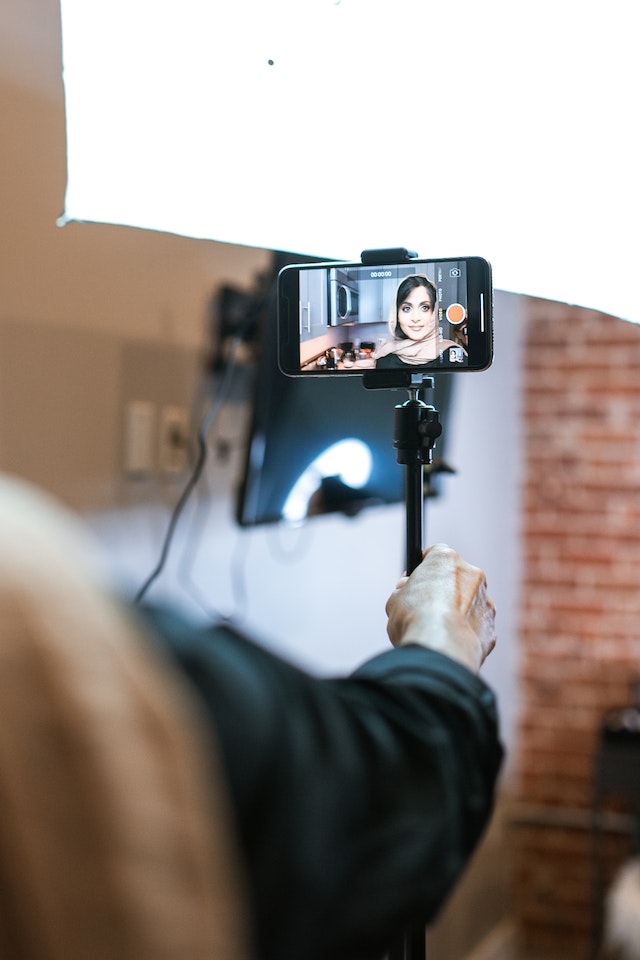 A girl in a hijab recording a video for TikTok.