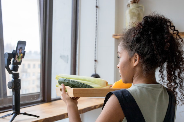 A girl recording a video of vegetables.