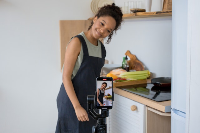 Uma garota cozinhando e gravando um vídeo para o TikTok.