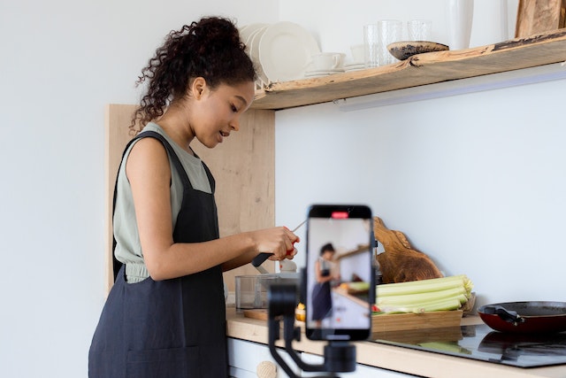 A woman cooking and recording a video for TikTok. 