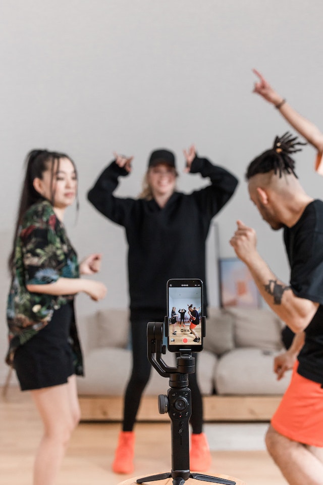 A woman and two men dancing for a TikTok video. 