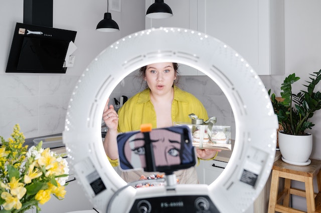 A woman recording a TikTok in her kitchen.