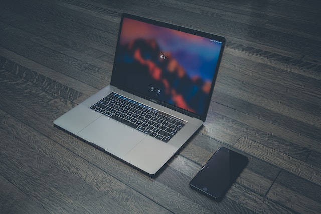 A laptop and an iPhone on a flat surface. 