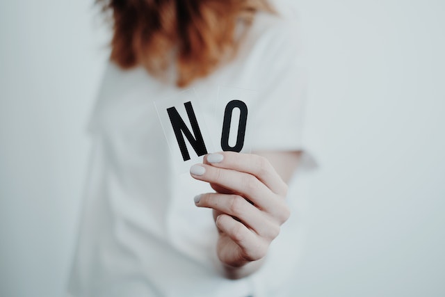 A close view of a woman holding the letters “NO.”