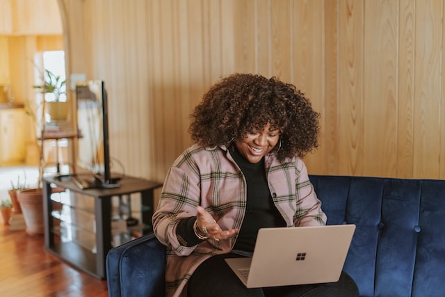 An influencer sitting and smiling happily at a view on her PC.