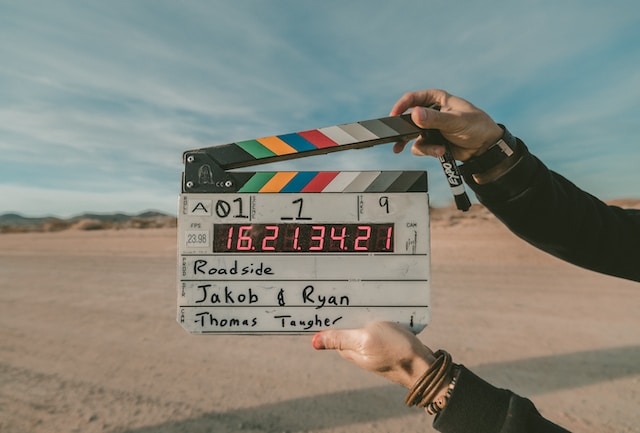 A person holding a clapboard in the desert.