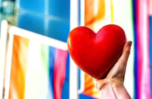 A person holding a red heart in one hand.