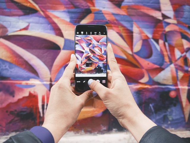 A person taking a video of wall graffiti.