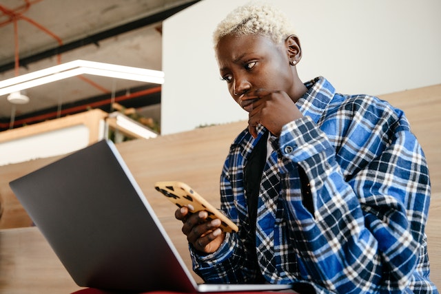 A user holding a phone and thinking of how to edit a caption on TikTok.