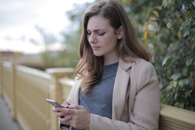 A woman standing outside and trying to figure out why her TikTok app is not working.