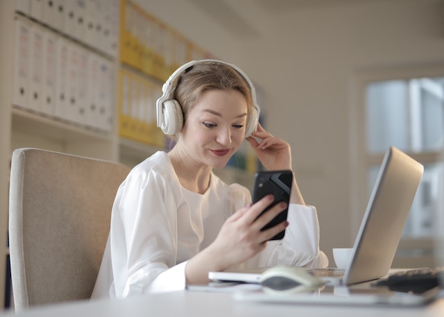 A young influencer smiling and scrolling through the TikTok app on her smartphone.