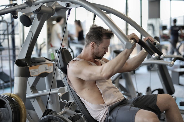 Een fitness influencer gebruikt een shoulder press in de sportschool.