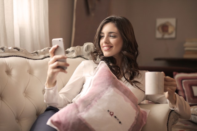 A woman watching a TikTok video and smiling while at it.