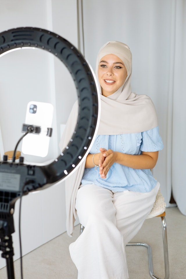 A girl sitting and talking while recording a video for TikTok.