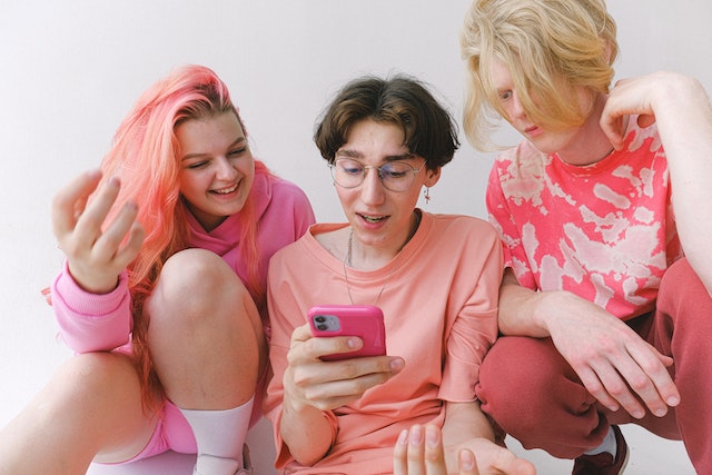 Three influencers searching for websites to buy TikTok usernames on a mobile device.