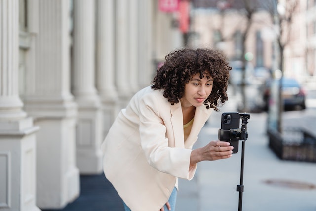 Een fashion influencer die op straat een video opneemt voor TikTok.