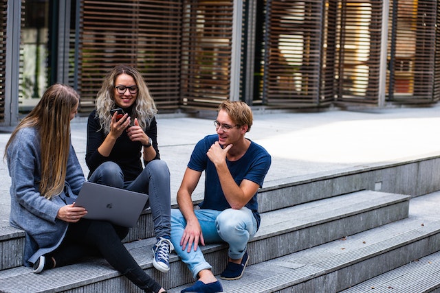 Three tech influencers sitting outside and discussing strategies to create content on TikTok.