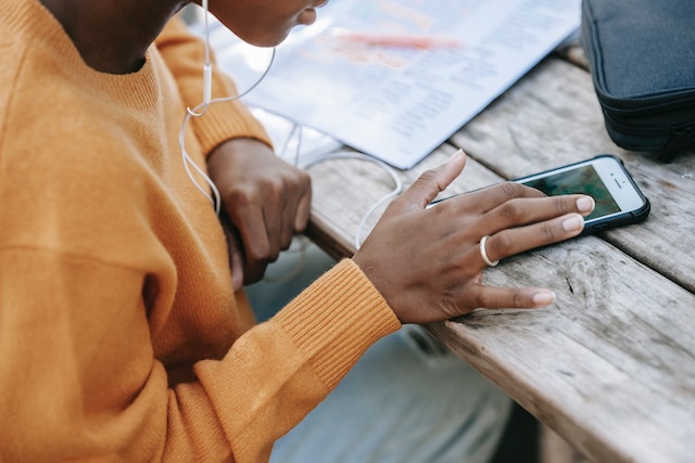 A young lady listening to music and searching for TikTok account checker tools on her smartphone.