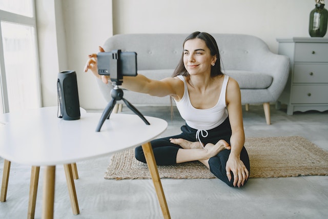A girl recording a video of herself doing yoga for TikTok.