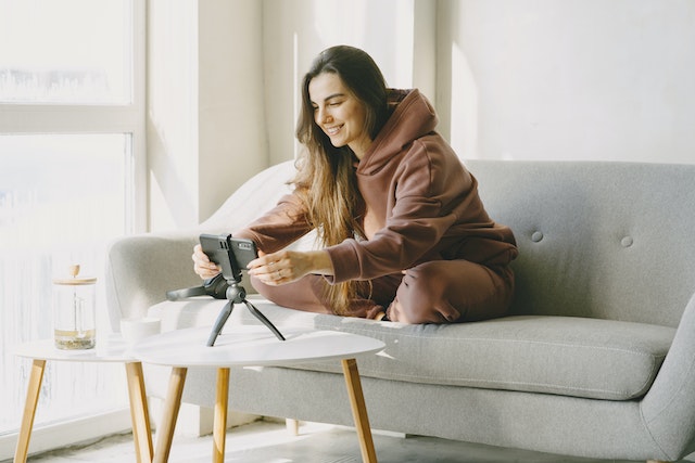 A woman smiling and recording a video for TikTok.