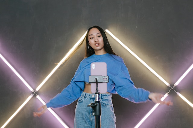 A girl in a blue sweater recording a video for TikTok.