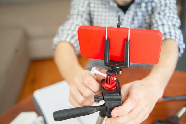 A tech influencer setting up his phone on a tripod to start making video content for his fans.