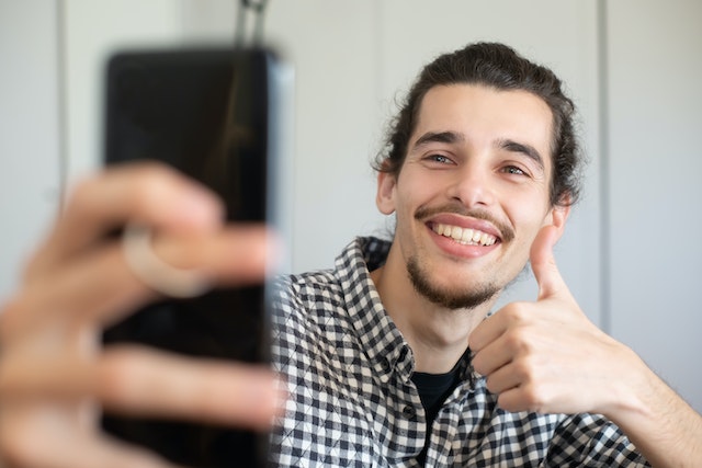 An influencer smiling happily at his phone.