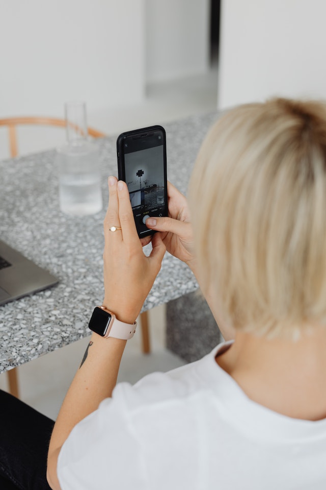 A girl holding her phone and recording a TikTok.