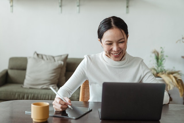 A TikTok influencer holding a pen and checking her audience data on a laptop.