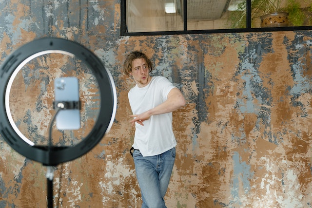 TikTokビデオのために踊りながら自分を録画する男性。 