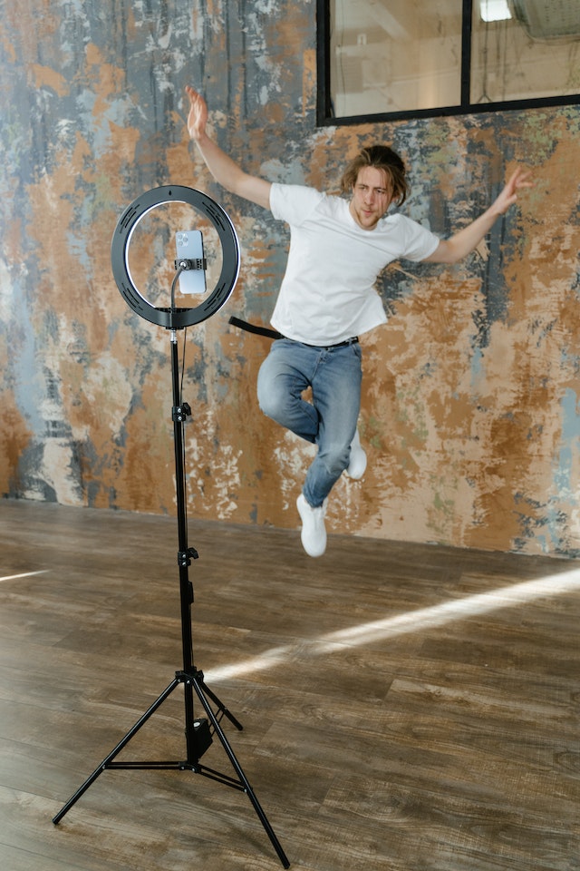 A man in a white shirt posing for a TikTok video.