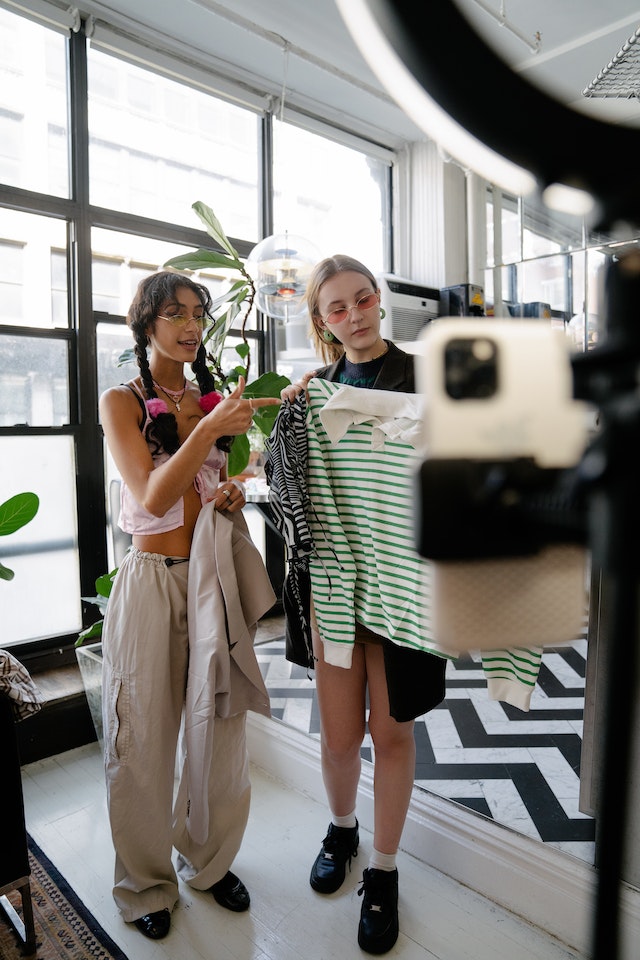 Duas garotas gravando um vídeo do TikTok sobre tendências da moda.